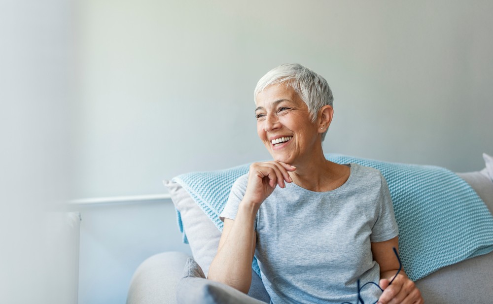 Senior woman smiling while sitting on her couch at home
