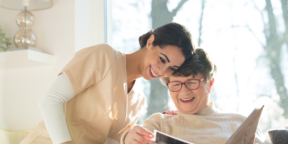 nurse reading a book with happy senior woman