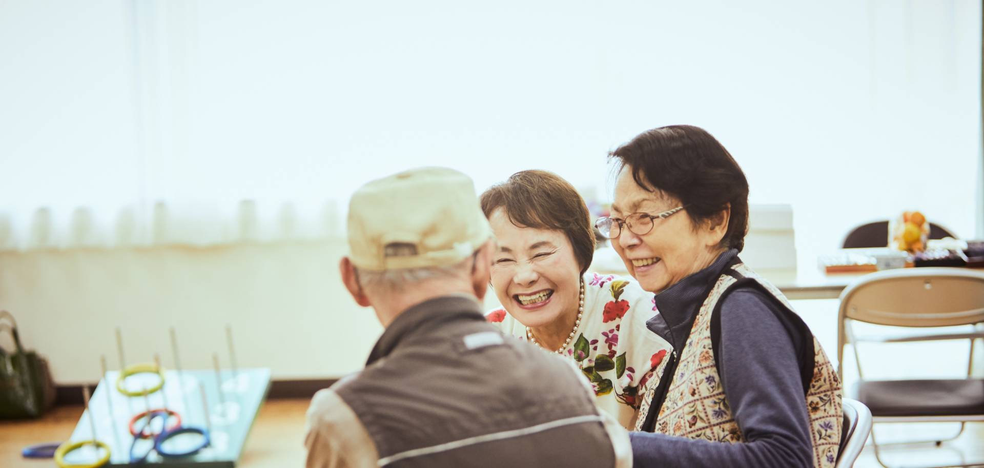 Two senior women happily looking at senior male