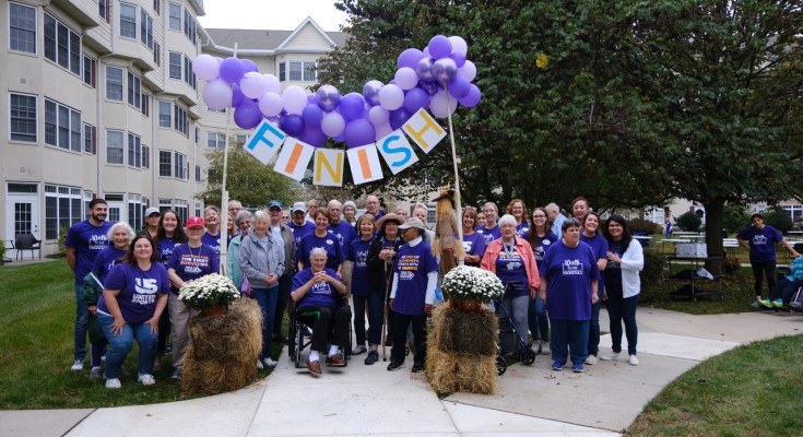 Residents and staff wearing purple at the balloon arch finish line for the Second Annual Walk to End Alzheimer's