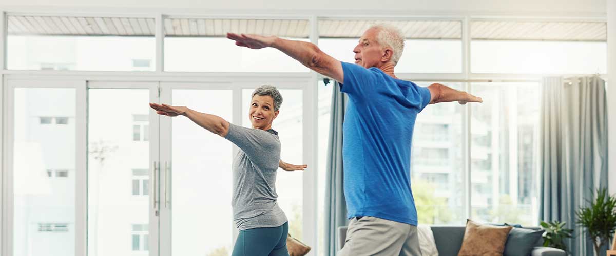 Senior couple doing yoga together inside their retirement community