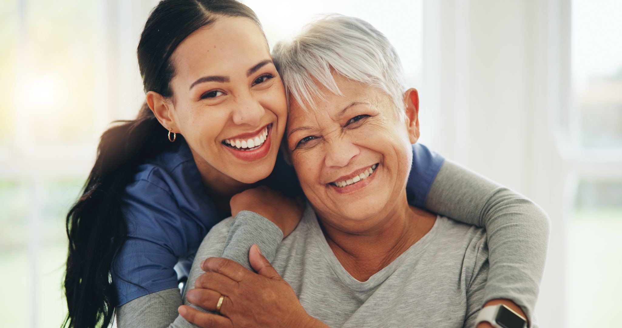 Happy female nurse hugging happy senior woman
